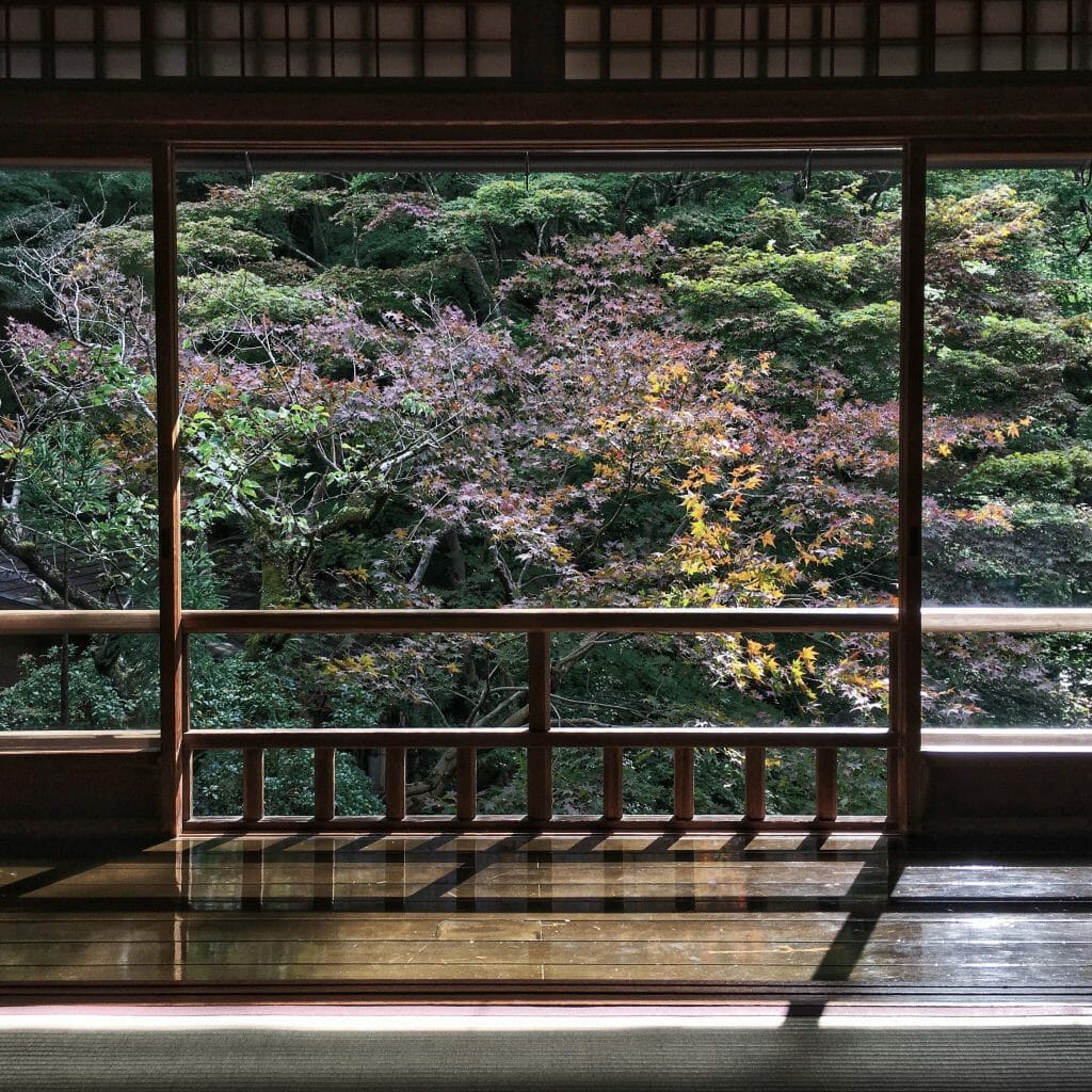 uitzicht tempel op bos achter Japans hekwerk